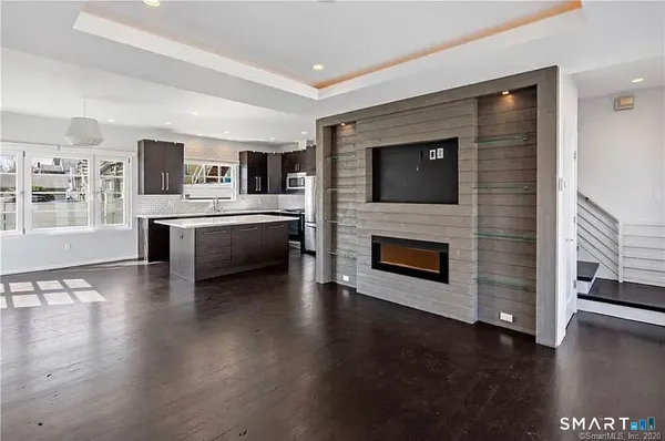 a living room with stainless steel appliances a fireplace a flat screen tv and view kitchen