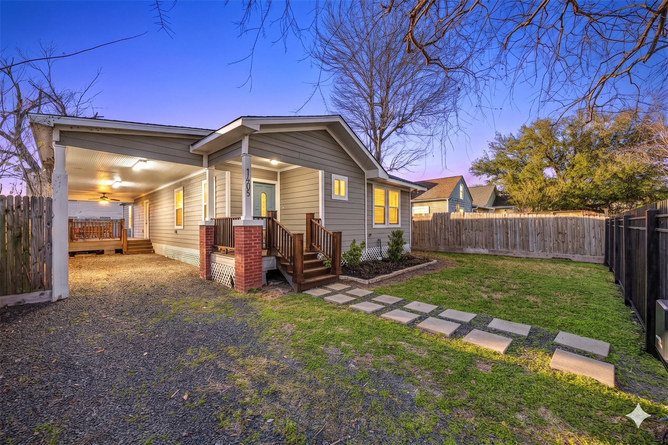 Charming cottage-style exterior with covered front porch, extended driveway for ample parking, and gated yard for added privacy.