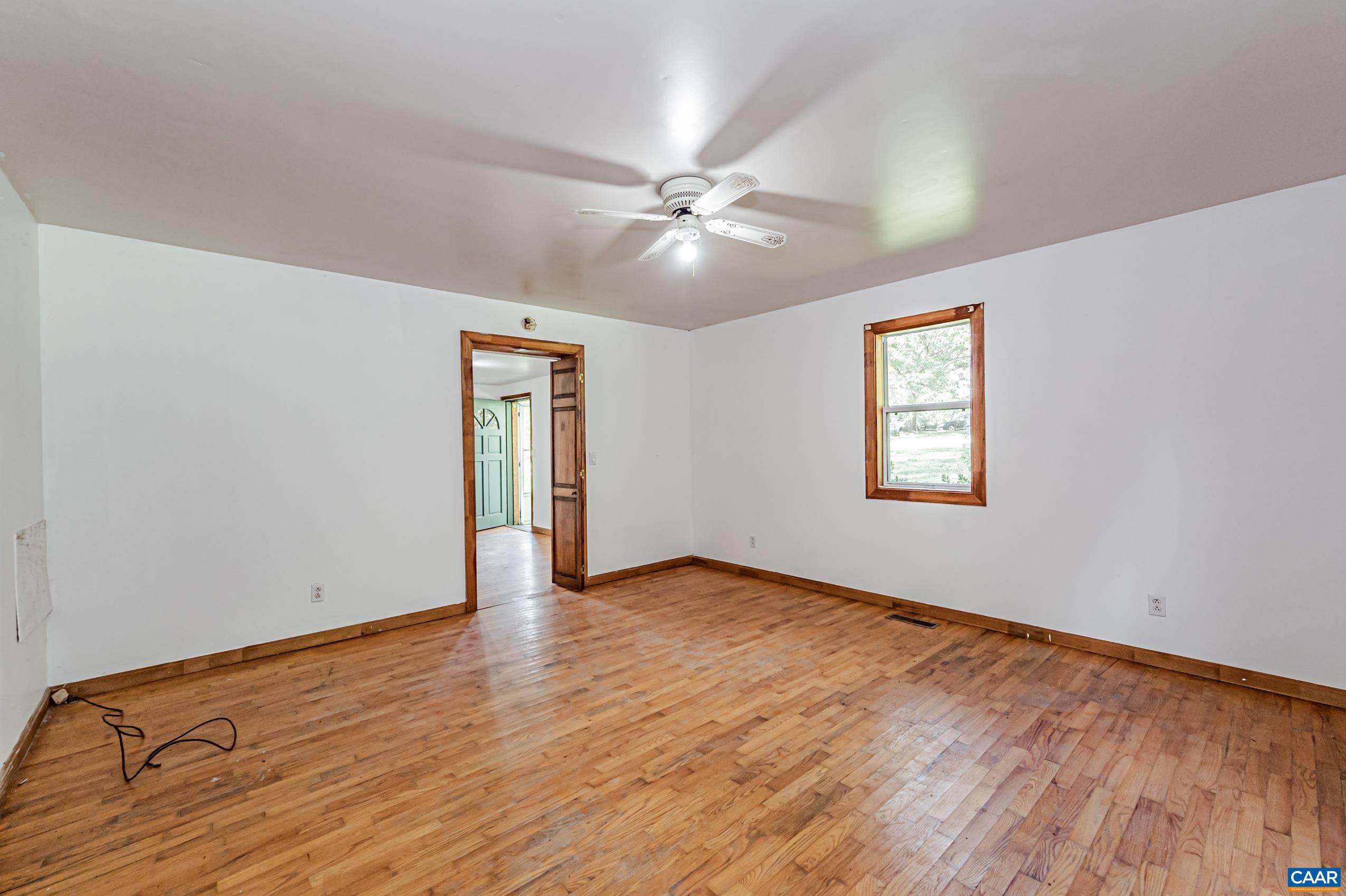431 Graves Mill Road Madison, VA 22727 - Photo 9 of 26 an empty room with wooden floor chandelier fan and windows