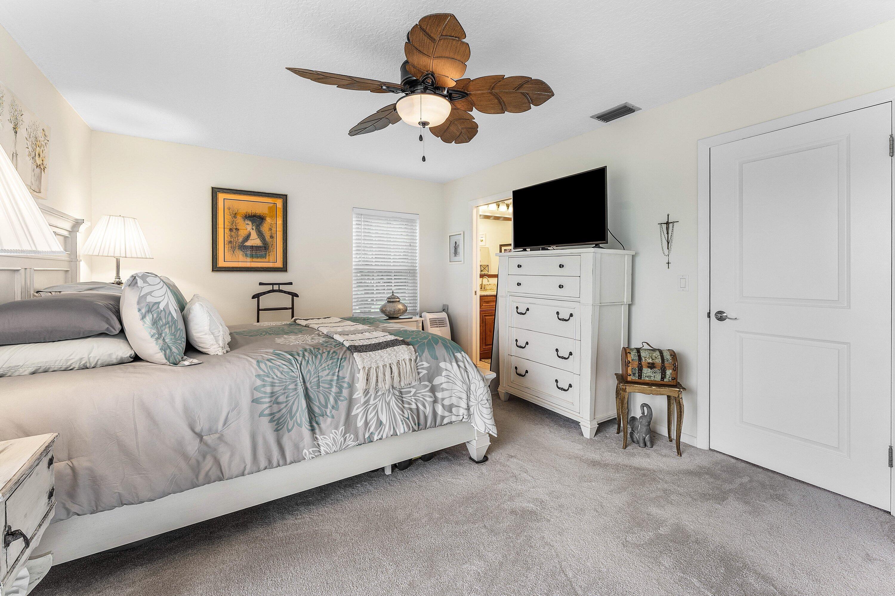 9179 Southeast Riverfront Terrace, Unit F Jupiter, FL 33469 - Photo 16 of 50 a bedroom with a bed and a flat screen tv
