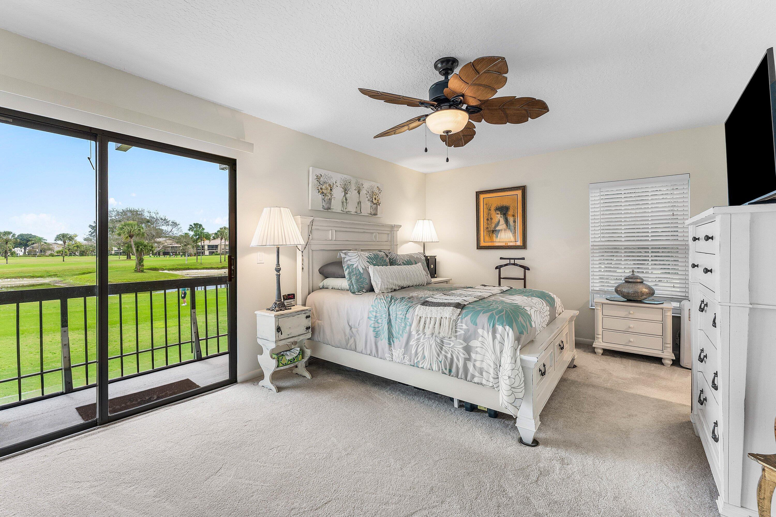 9179 Southeast Riverfront Terrace, Unit F Jupiter, FL 33469 - Photo 17 of 50 a bedroom with a bed and large windows