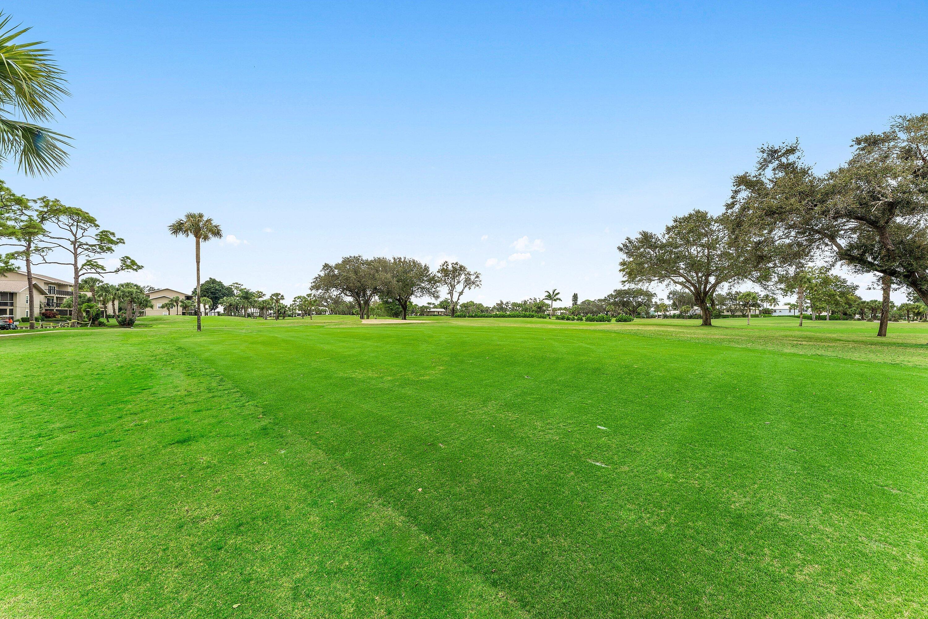 9179 Southeast Riverfront Terrace, Unit F Jupiter, FL 33469 - Photo 28 of 50 a view of a grassy field with an trees