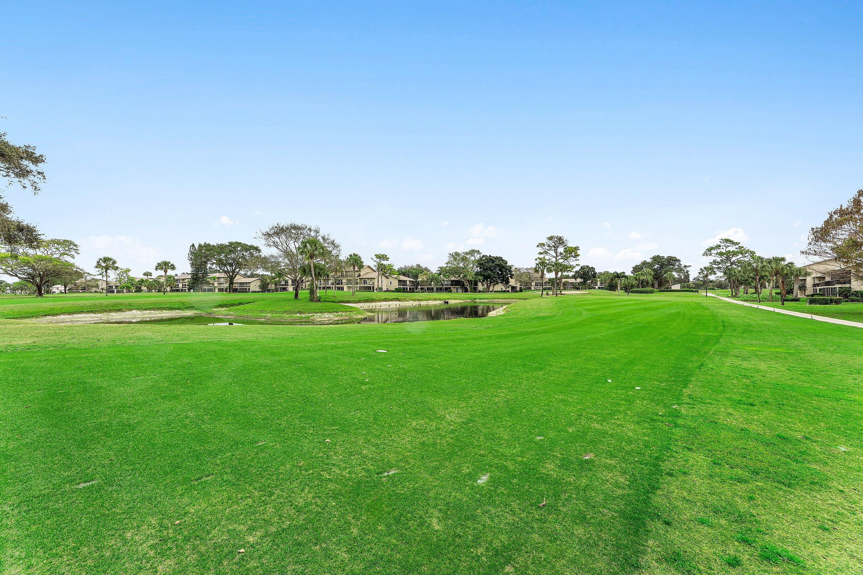 9179 Southeast Riverfront Terrace, Unit F Jupiter, FL 33469 - Photo 29 of 50 a view of grassy field with benches and trees all around