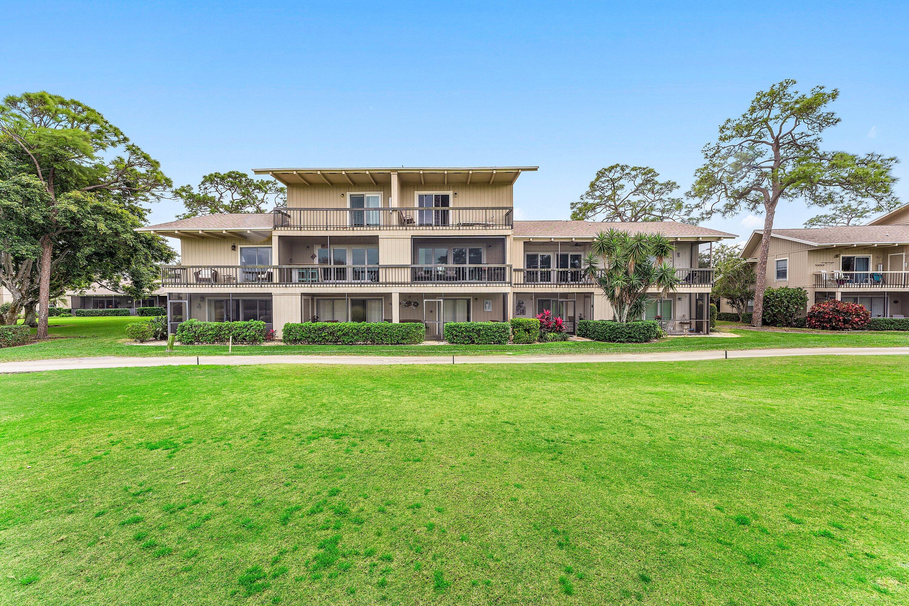9179 Southeast Riverfront Terrace, Unit F Jupiter, FL 33469 - Photo 30 of 50 a front view of a building with a garden