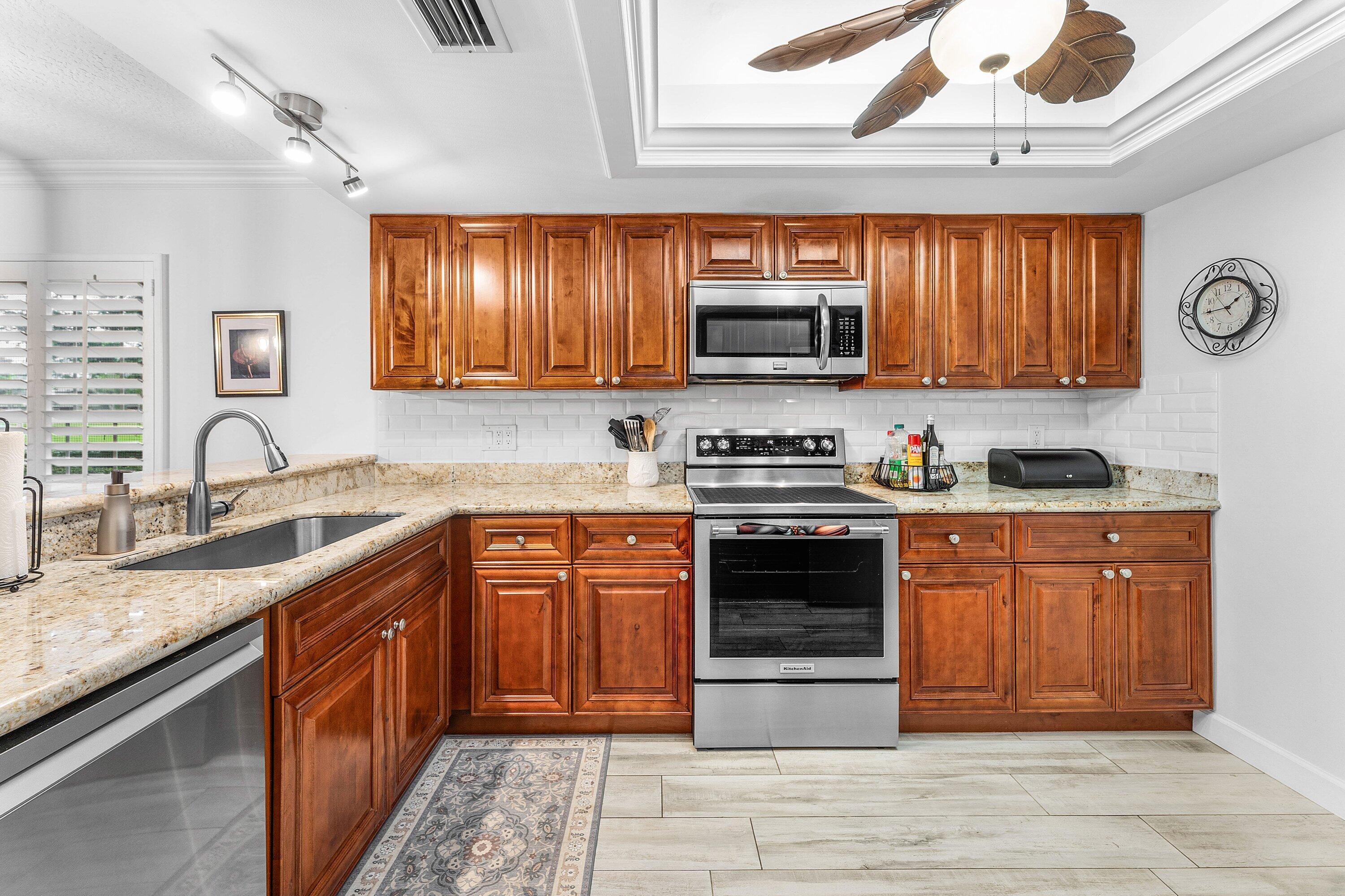 9179 Southeast Riverfront Terrace, Unit F Jupiter, FL 33469 - Photo 4 of 50 a kitchen with stainless steel appliances granite countertop a stove sink and microwave