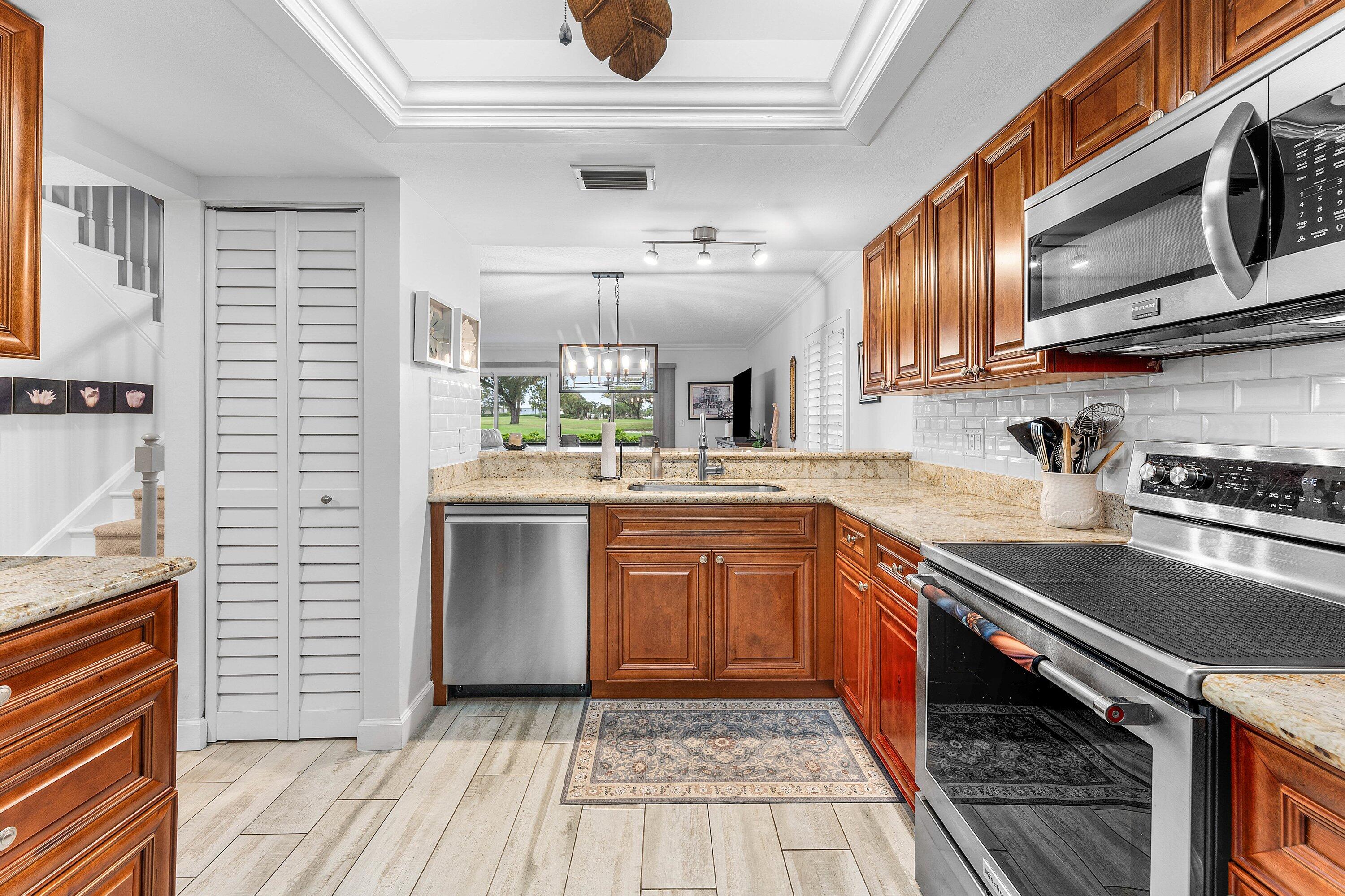 9179 Southeast Riverfront Terrace, Unit F Jupiter, FL 33469 - Photo 6 of 50 a kitchen with stainless steel appliances granite countertop a sink stove and cabinets