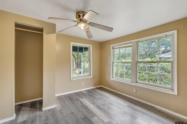 a view of an empty room with a window and wooden floor