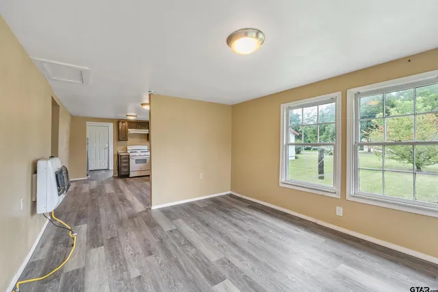 a view of empty room with wooden floor and fan