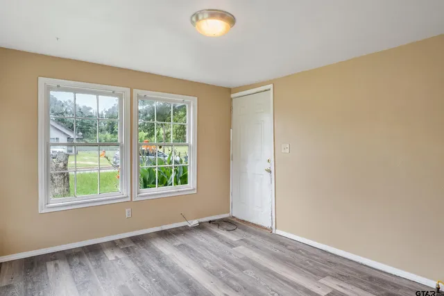 a view of an empty room with wooden floor and windows