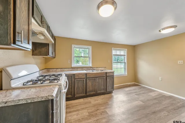 a kitchen with stainless steel appliances granite countertop a stove a sink and a microwave