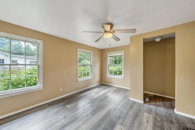 a view of empty room with wooden floor and fan