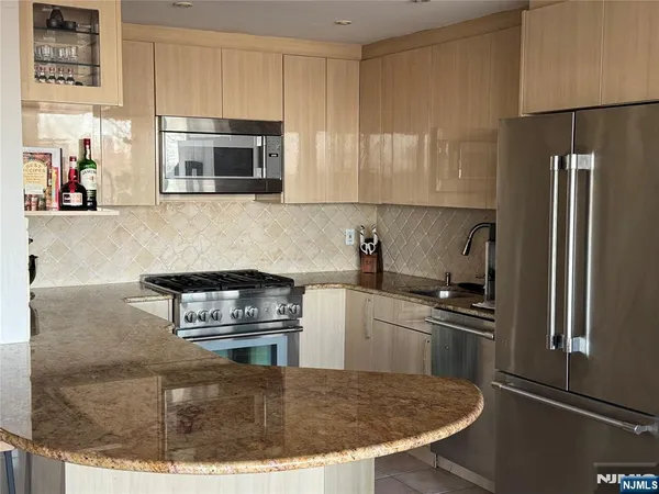 a kitchen with stainless steel appliances granite countertop a stove a sink and a refrigerator
