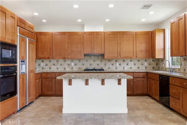 a kitchen with stainless steel appliances granite countertop a sink a stove and a refrigerator