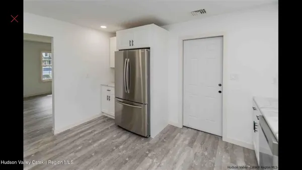 a view of a refrigerator in kitchen and an empty room