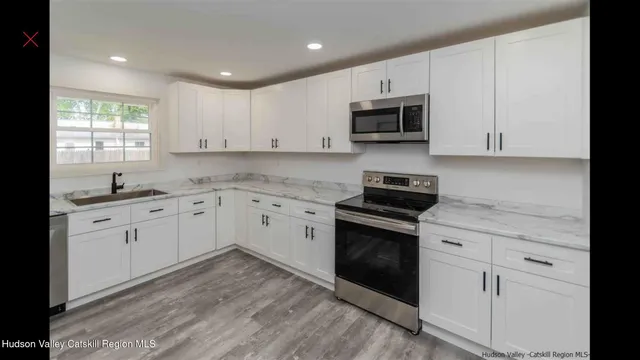 a kitchen with granite countertop white cabinets and stainless steel appliances