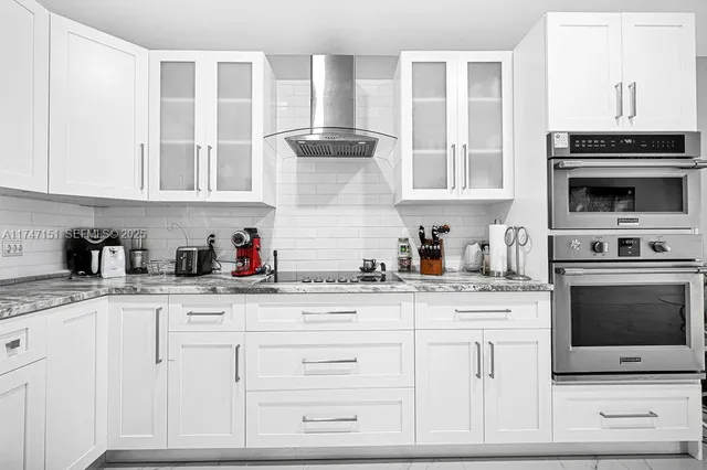 a kitchen with granite countertop white cabinets and stainless steel appliances
