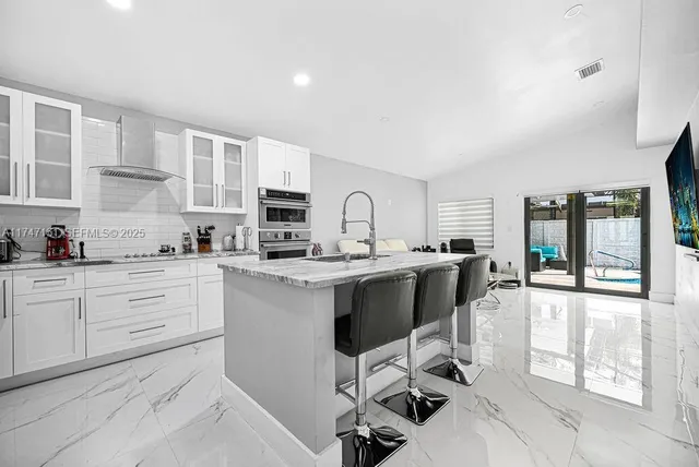 a kitchen with granite countertop white cabinets and stainless steel appliances