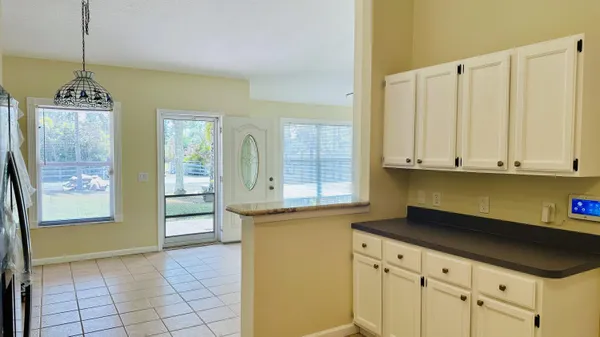 a kitchen with stainless steel appliances granite countertop a refrigerator a sink dishwasher and white cabinets with wooden floor