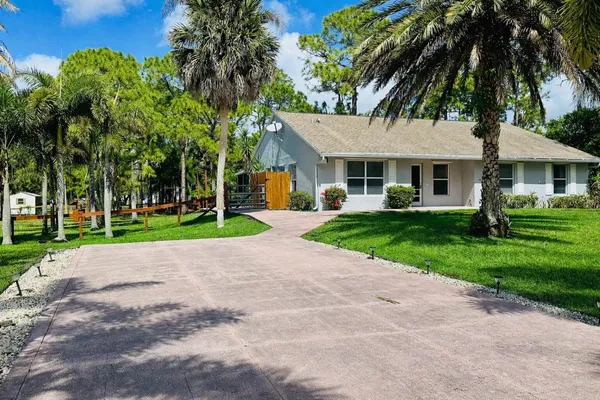front view of a house with a yard and palm trees