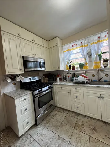 a kitchen with granite countertop white cabinets stainless steel appliances and a sink