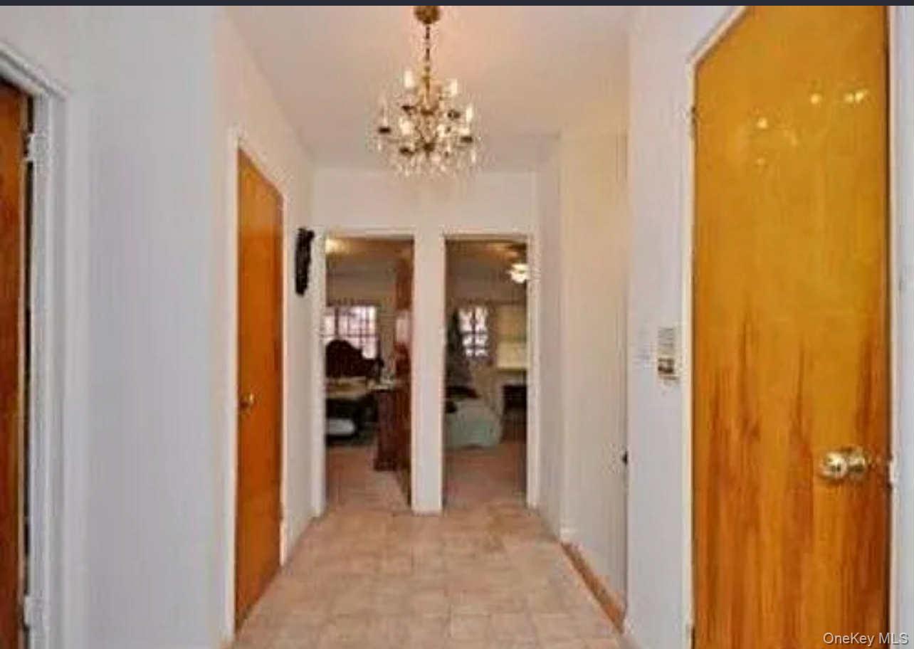 96-28 41st Avenue Queens, NY 11368 - Photo 5 of 5 Hallway with a chandelier and light tile patterned flooring