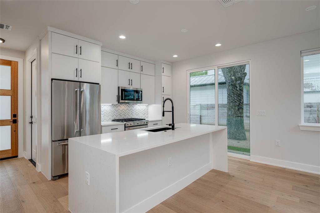 1406 East 2nd Street, Unit 2 Austin, TX 78702 - Photo 2 of 20 a kitchen with stainless steel appliances a refrigerator stove microwave and cabinets