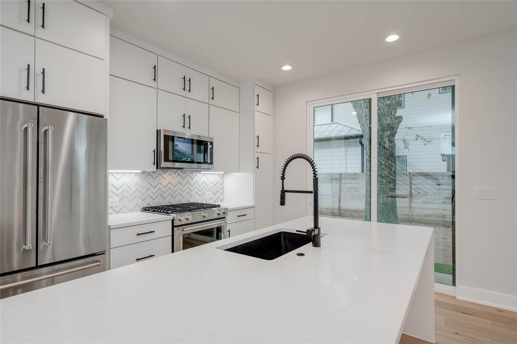 1406 East 2nd Street, Unit 2 Austin, TX 78702 - Photo 7 of 20 a kitchen with stainless steel appliances a refrigerator sink and white cabinets