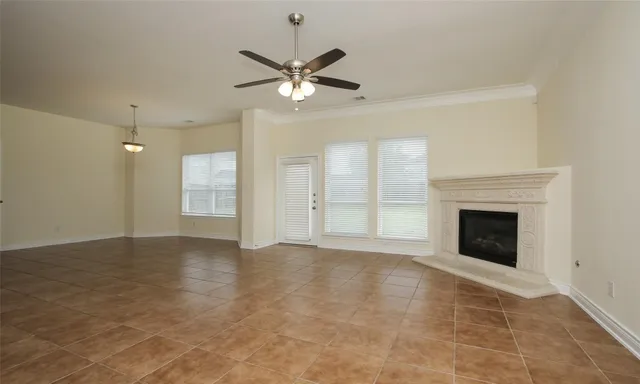 a view of an empty room with chandelier fan and fire place