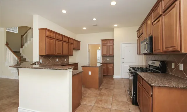 a kitchen with stainless steel appliances granite countertop a stove top oven a sink and a refrigerator