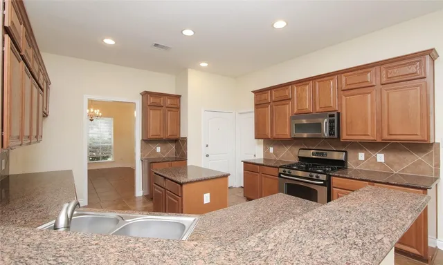 a kitchen with stainless steel appliances granite countertop a stove a sink and a refrigerator