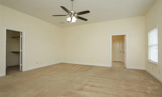 an empty room with windows and fan