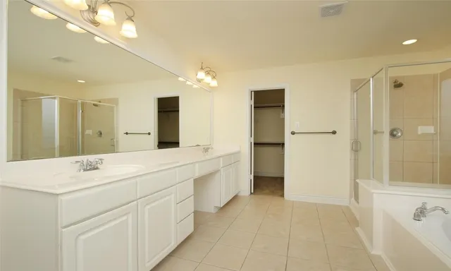 a spacious bathroom with a shower a sink and a mirror