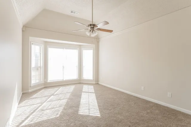 an empty room with windows and fan