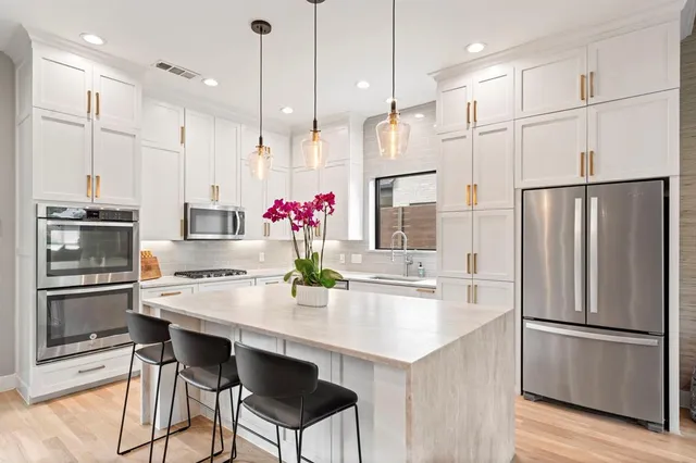 a kitchen with granite countertop a table chairs stainless steel appliances and wooden floor