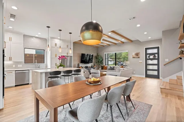 a kitchen with stainless steel appliances granite countertop a stove a sink a dining table and chairs with wooden floor