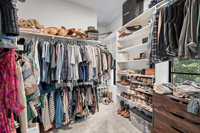 a view of walk in closet with clothes and shoes