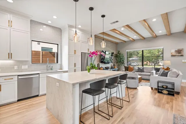a kitchen that has a lot of cabinets a sink a stove and wooden floor