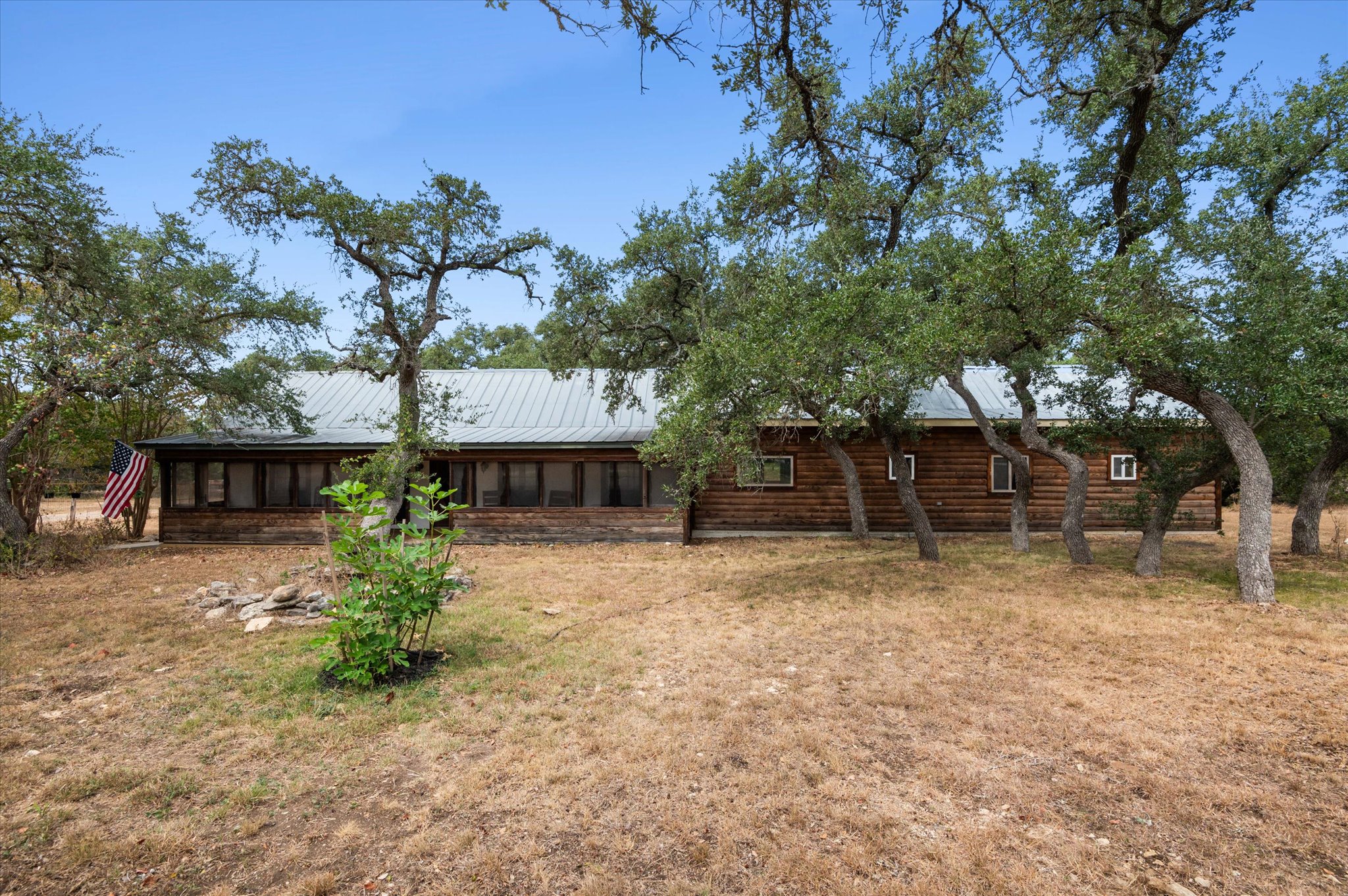 215 Go Away Road Blanco, TX 78606 - Photo 4 of 30 Charming Hill Country home on 4.16 acres surrounded by mature oak trees — fully gated and fenced for privacy. Relax on the screened in front porch and enjoy sunrises and sunsets and wildlife in a tranquil relaxing setting. Go Away Road in name only — once you’re here, you’ll want to stay.