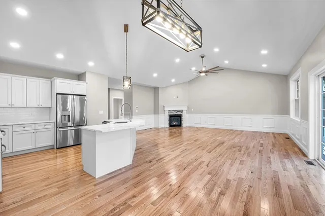 a large kitchen with kitchen island a stove a sink dishwasher and a oven with white cabinets