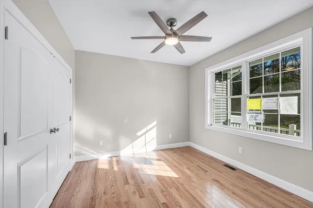 a view of empty room with wooden floor and fan