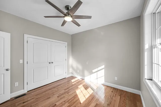 a view of empty room with wooden floor and fan
