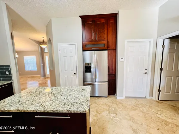 a view of kitchen with granite countertop cabinets and refrigerator