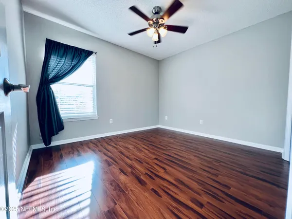 a view of an empty room with window and wooden floor