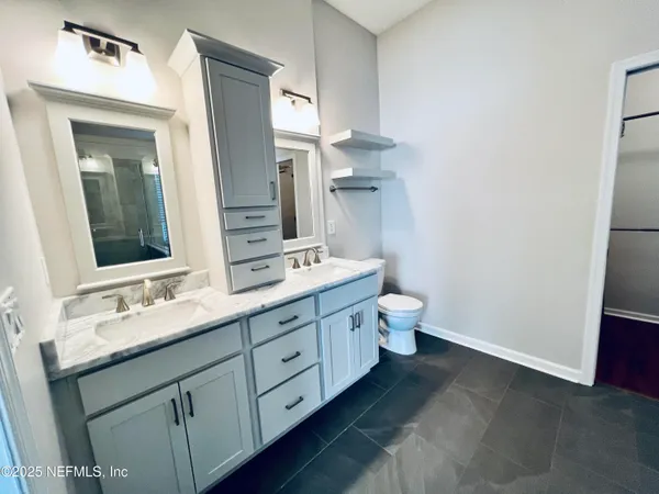 a bathroom with a double vanity sink toilet and mirror
