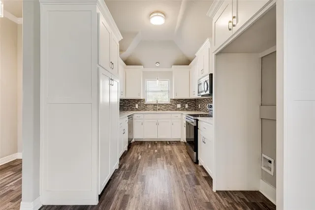a kitchen with a refrigerator a sink and wooden floor