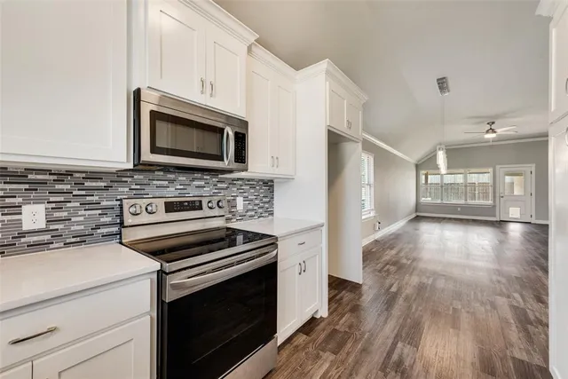 a kitchen with a stove a microwave and wooden floor