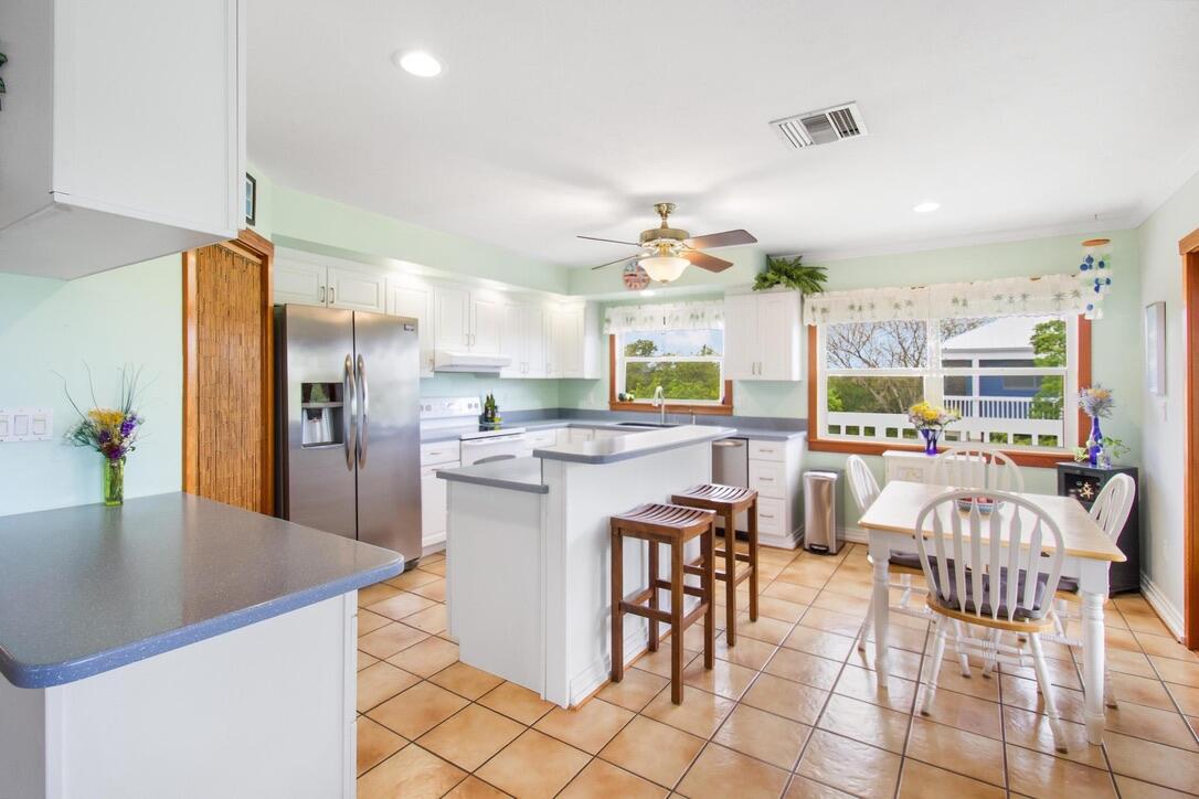 25057 7th Street Summerland Key, FL 33042 - Photo 19 of 43 a kitchen with stainless steel appliances kitchen island granite countertop a table chairs and a refrigerator