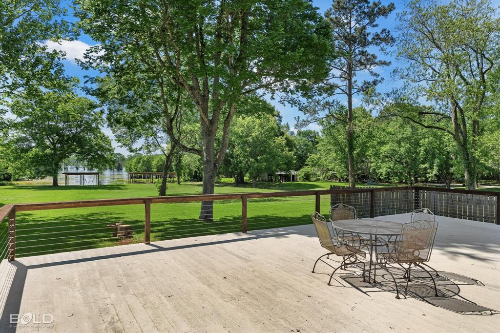 225 Marie Road Ringgold, LA 71068 - Photo 2 of 40 Spacious outdoor deck featuring a light-toned surface, wood railing with cable infill, and a lush green lawn