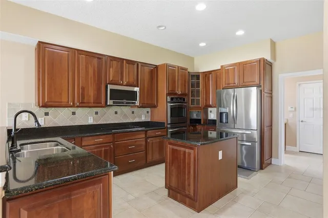 a kitchen with stainless steel appliances granite countertop a stove a sink dishwasher a refrigerator and a microwave oven with wooden cabinets