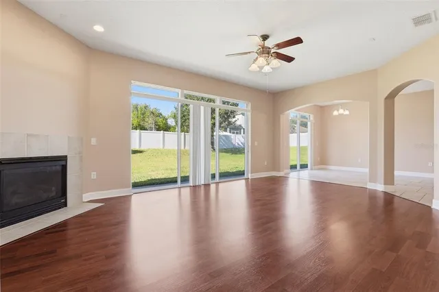 an empty room with wooden floor fireplace and windows